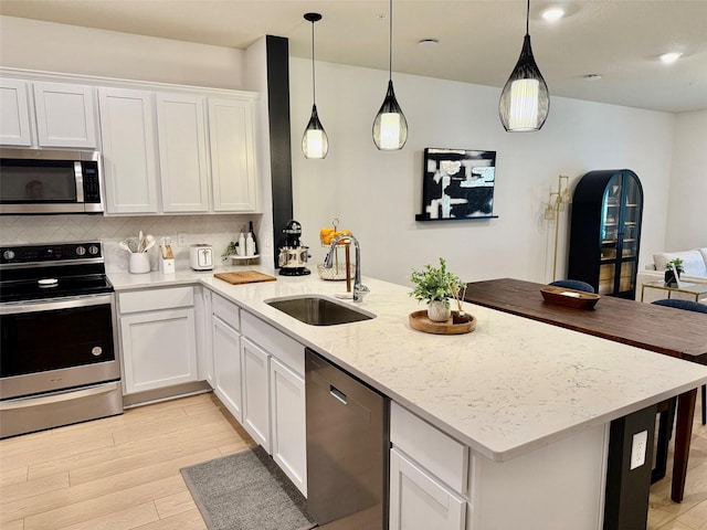 1900 Erudite Way, Winter Park, FL 32792 - kitchen featuring stainless steel appliances, a sink, light wood finished floors, a peninsula, and white cabinets