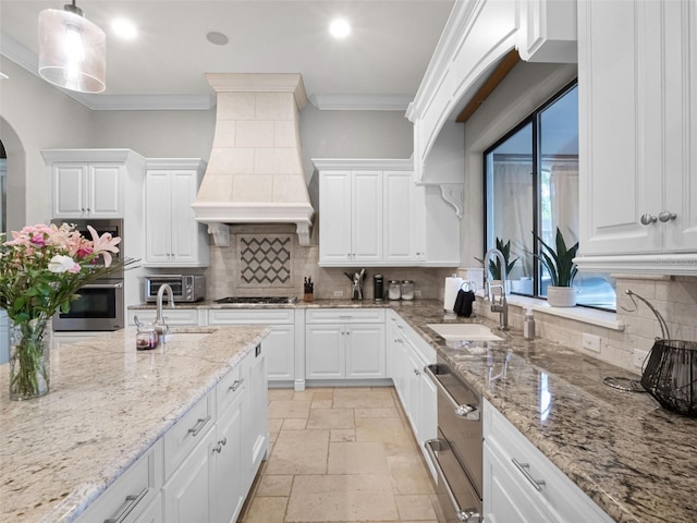 1417 Terralago Pl, Oviedo, FL 32765 - kitchen with a sink, custom range hood, stone tile flooring, white cabinets, and ornamental molding