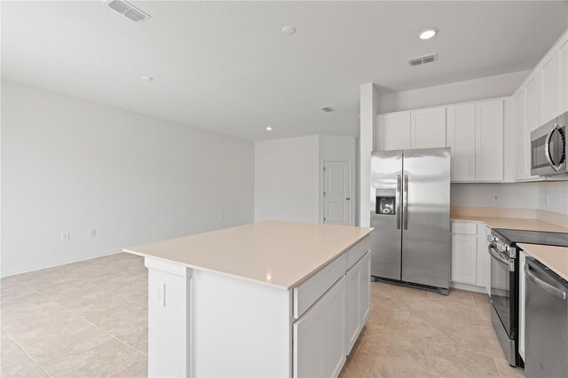 2716 Pierr St, Davenport, FL 33837 - kitchen with appliances with stainless steel finishes, light countertops, a kitchen island, white cabinetry, and recessed lighting
