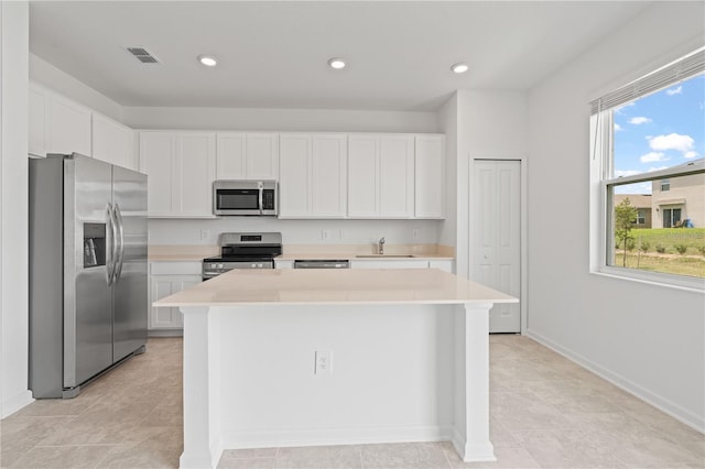 2716 Pierr St, Davenport, FL 33837 - kitchen with appliances with stainless steel finishes, light countertops, a kitchen island, white cabinetry, and recessed lighting