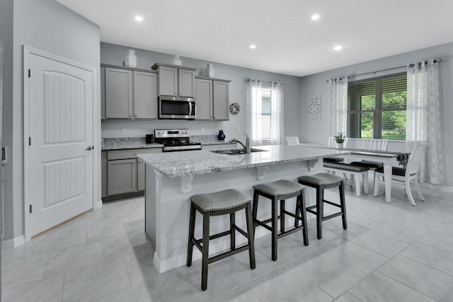 1580 Delphi Way, New Smyrna Beach, FL 32168 - kitchen with stainless steel appliances, gray cabinetry, a kitchen bar, recessed lighting, and a center island with sink