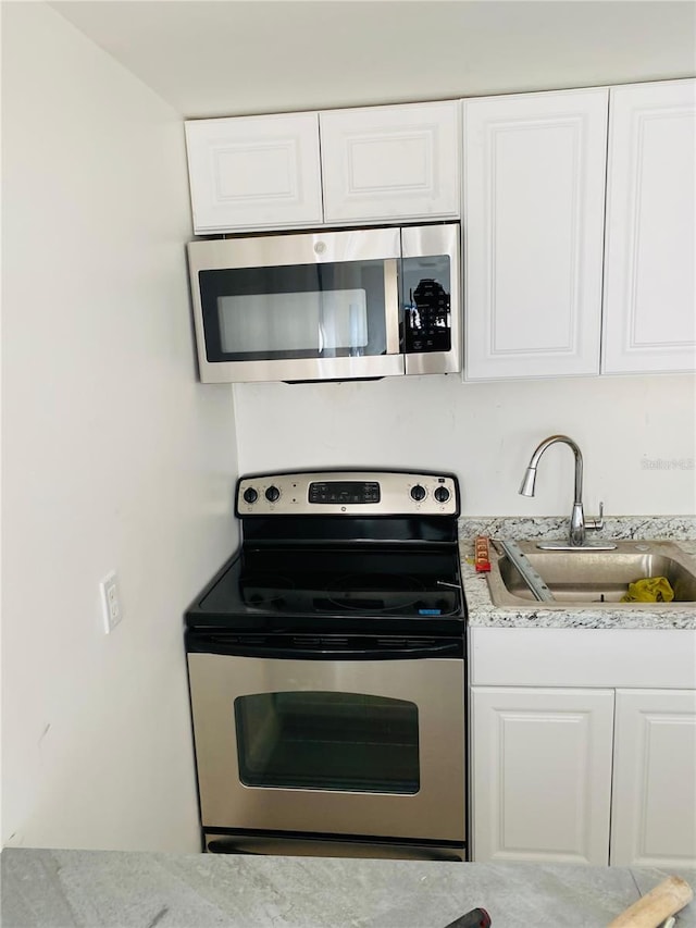 8612 N Alaska St, Tampa, FL 33604 - kitchen featuring appliances with stainless steel finishes, a sink, and white cabinetry