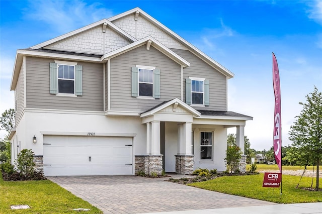 1262 Champions Dr, Daytona Beach, FL 32124 - craftsman inspired home with stone siding, a front lawn, a garage, decorative driveway, and covered porch