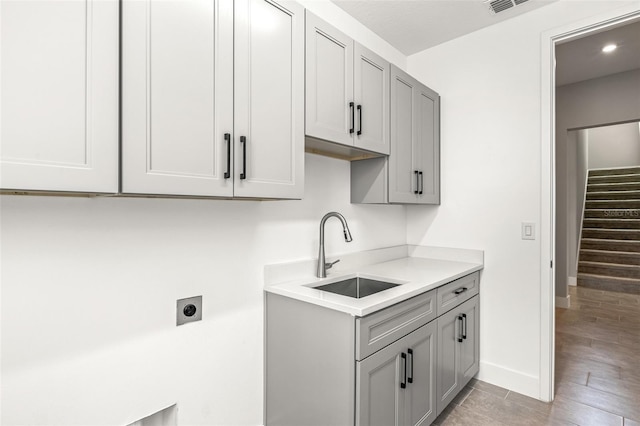 1262 Champions Dr, Daytona Beach, FL 32124 - washroom featuring electric dryer hookup, cabinet space, baseboards, and light wood-type flooring