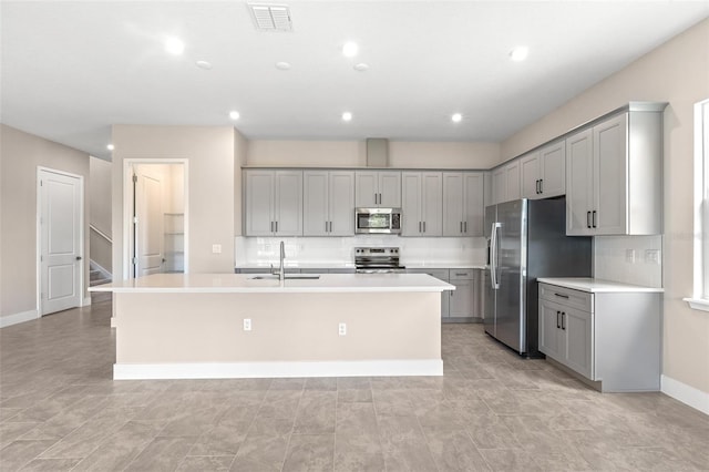 1262 Champions Dr, Daytona Beach, FL 32124 - kitchen with appliances with stainless steel finishes, a sink, gray cabinets, a kitchen island with sink, and recessed lighting