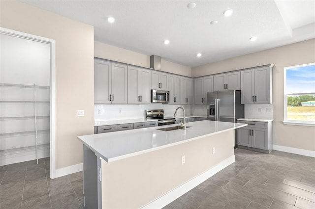 1262 Champions Dr, Daytona Beach, FL 32124 - kitchen featuring appliances with stainless steel finishes, gray cabinetry, a sink, a center island with sink, and light countertops