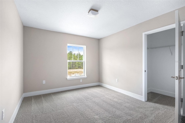 1262 Champions Dr, Daytona Beach, FL 32124 - unfurnished bedroom featuring carpet flooring, a walk in closet, baseboards, a closet, and a textured ceiling