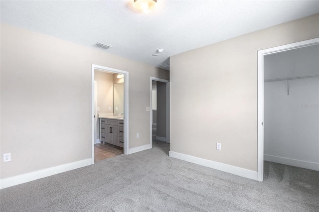 1262 Champions Dr, Daytona Beach, FL 32124 - unfurnished bedroom with light carpet, a walk in closet, a closet, baseboards, and ensuite bath