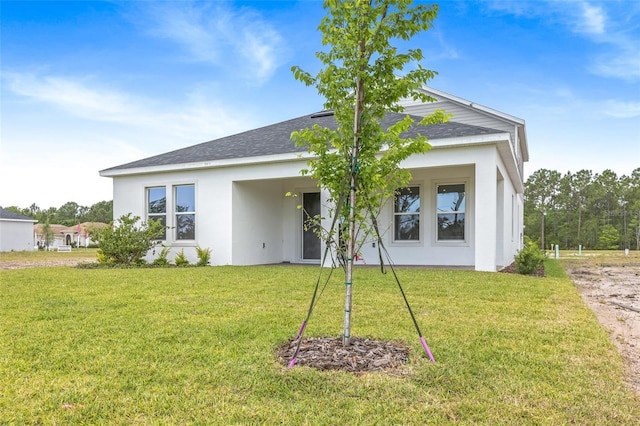 1262 Champions Dr, Daytona Beach, FL 32124 - back of house featuring stucco siding, a lawn, and a shingled roof