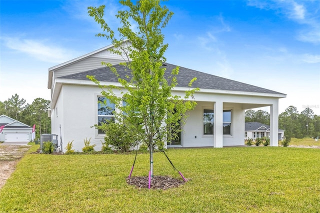 1262 Champions Dr, Daytona Beach, FL 32124 - back of property featuring a yard, roof with shingles, central AC unit, and stucco siding