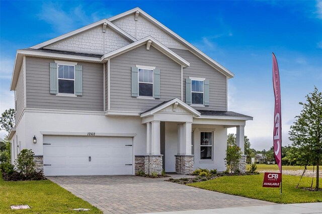 1262 Champions Dr, Daytona Beach, FL 32124 - craftsman-style home with stone siding, an attached garage, a front lawn, and decorative driveway
