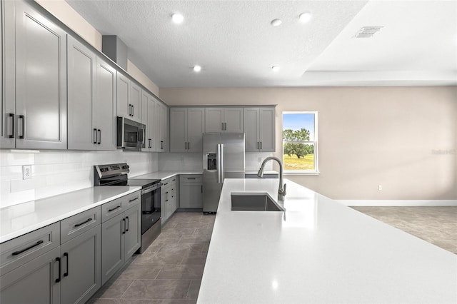 1262 Champions Dr, Daytona Beach, FL 32124 - kitchen featuring appliances with stainless steel finishes, a sink, gray cabinets, decorative backsplash, and light countertops