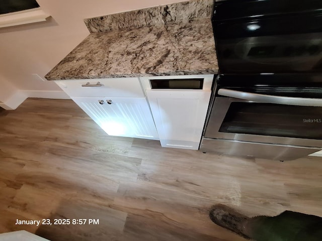 6505 Oelsner St, New Port Richey, FL 34652 - kitchen view of wood finished floors, white cabinetry, light stone countertops, baseboards, and multiple ovens