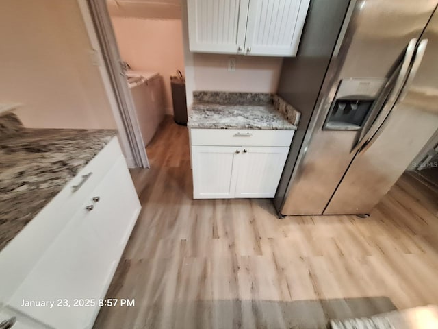 6505 Oelsner St, New Port Richey, FL 34652 - kitchen featuring stainless steel fridge with ice dispenser, light wood finished floors, white cabinets, and light stone counters
