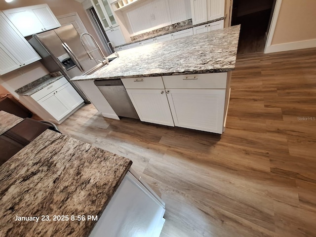 6505 Oelsner St, New Port Richey, FL 34652 - kitchen featuring wood finished floors, white cabinetry, a center island, and light stone counters