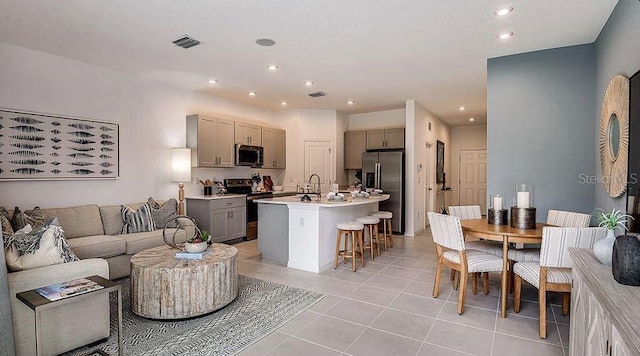 2208 Portrait St, Kissimmee, FL 34758 - kitchen with appliances with stainless steel finishes, gray cabinets, a kitchen bar, open floor plan, and light tile patterned flooring