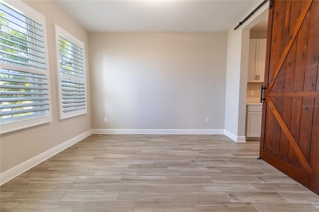 4861 Antrim Dr, Sarasota, FL 34240 - spare room featuring a barn door and light wood-type flooring