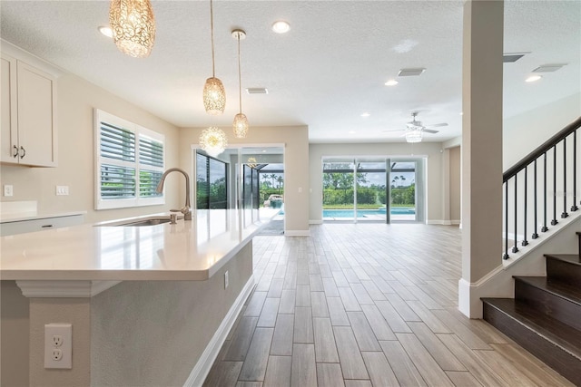 4861 Antrim Dr, Sarasota, FL 34240 - kitchen with white cabinetry, wood finished floors, light countertops, an island with sink, and pendant lighting