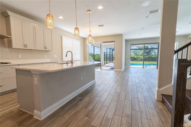 4861 Antrim Dr, Sarasota, FL 34240 - kitchen featuring light wood-style flooring, light countertops, a center island with sink, recessed lighting, and white cabinetry