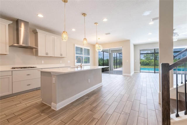 4861 Antrim Dr, Sarasota, FL 34240 - kitchen featuring wall chimney exhaust hood, light countertops, a kitchen island with sink, light wood-style floors, and recessed lighting