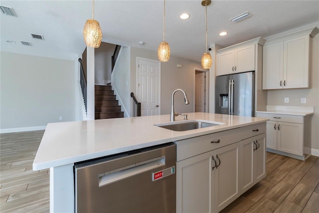 4861 Antrim Dr, Sarasota, FL 34240 - kitchen with appliances with stainless steel finishes, light wood finished floors, light countertops, white cabinets, and hanging light fixtures