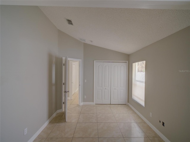 879 Nonastone Run, Casselberry, FL 32707 - unfurnished bedroom with lofted ceiling, light tile patterned flooring, a closet, a textured ceiling, and baseboards
