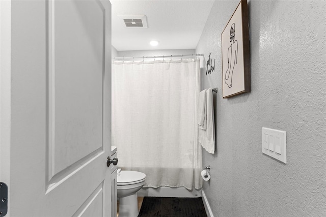 122 Seville Rd, Auburndale, FL 33823 - bathroom with a textured wall, toilet, wood finished floors, and shower / bath combo