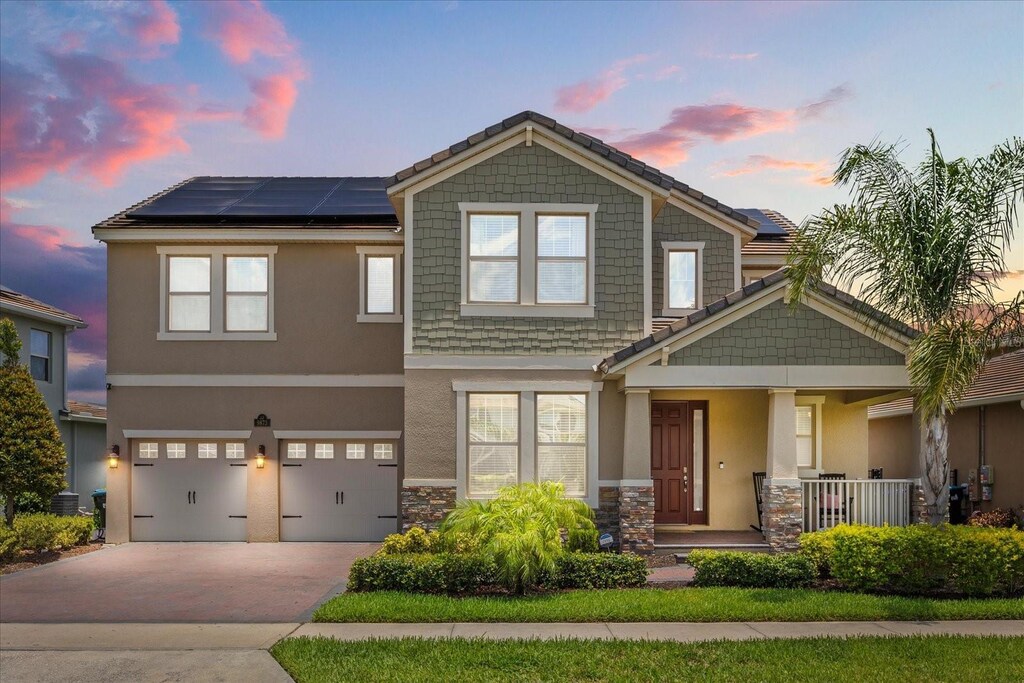 9873 Lost Creek Dr, Winter Garden, FL 34787 - craftsman house with a porch, stone siding, solar panels, concrete driveway, and a garage
