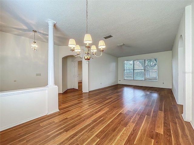1131 Turtle Lake Ct, Ocoee, FL 34761 - empty room featuring wood finished floors, arched walkways, a chandelier, a textured ceiling, and decorative columns