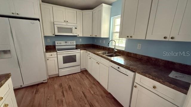 30965 E Thyme Ave, Eustis, FL 32736 - kitchen featuring white appliances, a sink, dark countertops, white cabinets, and light wood finished floors