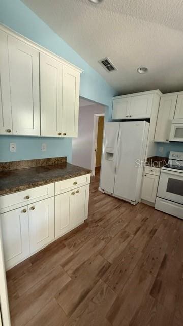 30965 E Thyme Ave, Eustis, FL 32736 - kitchen featuring white appliances, dark countertops, a textured ceiling, wood finished floors, and white cabinets