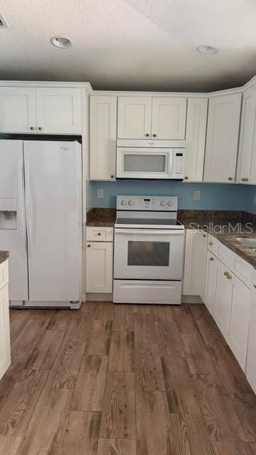 30965 E Thyme Ave, Eustis, FL 32736 - kitchen with white appliances, dark countertops, light wood-type flooring, white cabinetry, and recessed lighting