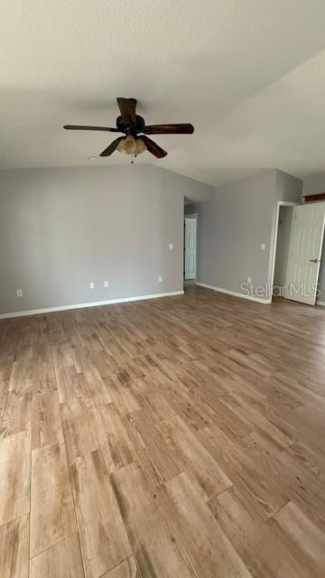 30965 E Thyme Ave, Eustis, FL 32736 - spare room with wood finished floors, a ceiling fan, baseboards, and vaulted ceiling