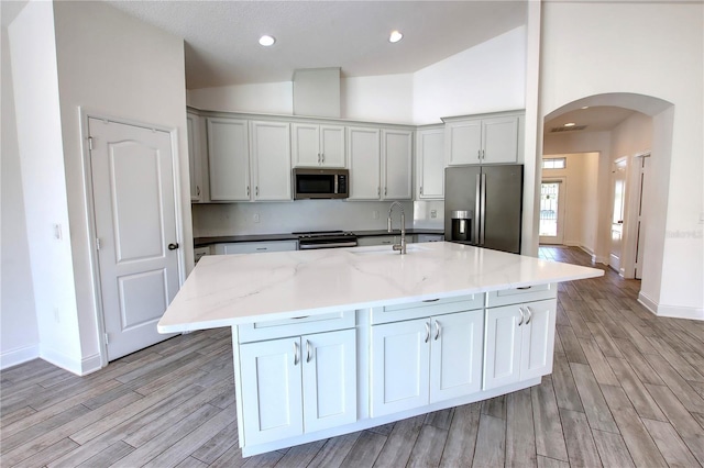 1727 Butterfly Way, Longwood, FL 32750 - kitchen featuring stainless steel appliances, arched walkways, a sink, light wood-style flooring, and baseboards