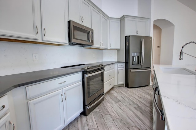 1727 Butterfly Way, Longwood, FL 32750 - kitchen featuring appliances with stainless steel finishes, a sink, light wood finished floors, and arched walkways