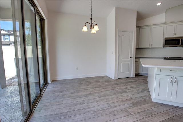 1727 Butterfly Way, Longwood, FL 32750 - kitchen featuring stainless steel microwave, a chandelier, light wood-style floors, vaulted ceiling, and hanging light fixtures