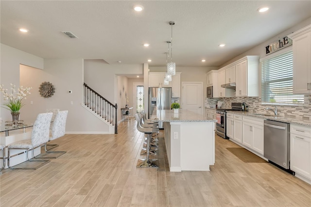 2793 Nature View Rd, Saint Cloud, FL 34771 - kitchen with appliances with stainless steel finishes, a kitchen breakfast bar, a sink, backsplash, and a center island