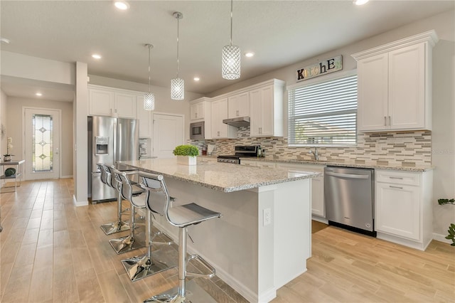 2793 Nature View Rd, Saint Cloud, FL 34771 - kitchen featuring stainless steel appliances, under cabinet range hood, a center island, tasteful backsplash, and white cabinetry
