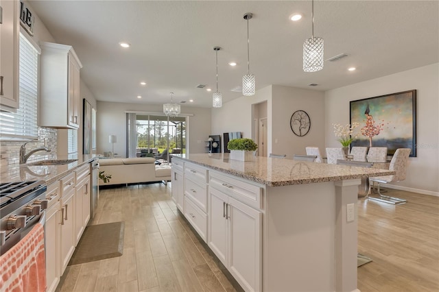 2793 Nature View Rd, Saint Cloud, FL 34771 - kitchen with light wood-style floors, recessed lighting, a kitchen island, stainless steel appliances, and light stone counters