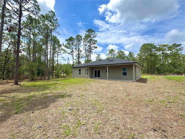 628 W Heronsbill Ln, Dunnellon, FL 34434 - back of house featuring a lawn and stucco siding
