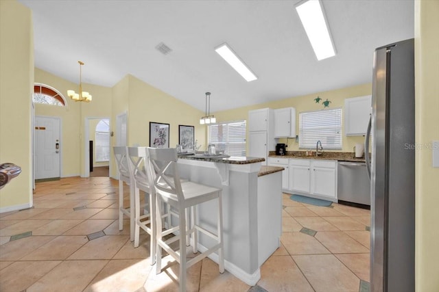 2627 Autumn Creek Cir, Kissimmee, FL 34747 - kitchen with stainless steel appliances, light tile patterned floors, lofted ceiling, white cabinets, and a breakfast bar