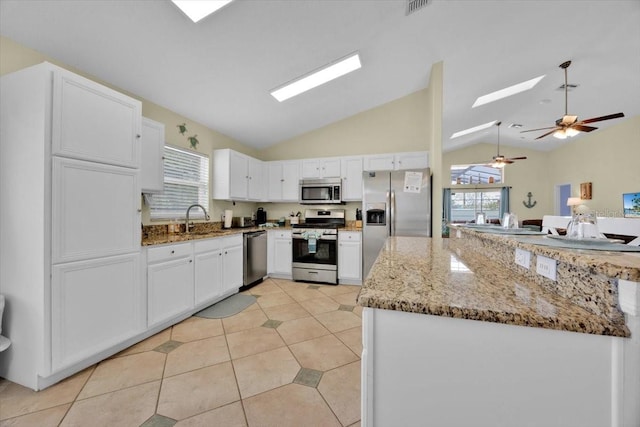 2627 Autumn Creek Cir, Kissimmee, FL 34747 - kitchen with stainless steel appliances, vaulted ceiling, a ceiling fan, a skylight, and white cabinetry