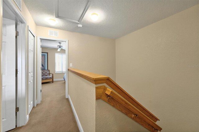 3725 Calabria Ave, Davenport, FL 33897 - hallway with light carpet, a textured ceiling, an upstairs landing, baseboards, and a textured wall