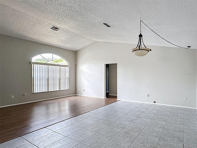 7337 Cone Shell Dr, Spring Hill, FL 34607 - empty room with tile patterned floors, vaulted ceiling, baseboards, and a textured ceiling