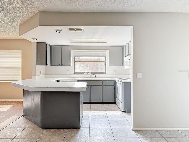 7337 Cone Shell Dr, Spring Hill, FL 34607 - kitchen featuring white appliances, gray cabinets, a peninsula, light tile patterned floors, and light countertops