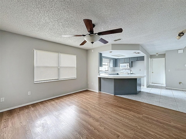 7337 Cone Shell Dr, Spring Hill, FL 34607 - kitchen with white microwave, light wood finished floors, light countertops, a peninsula, and a ceiling fan