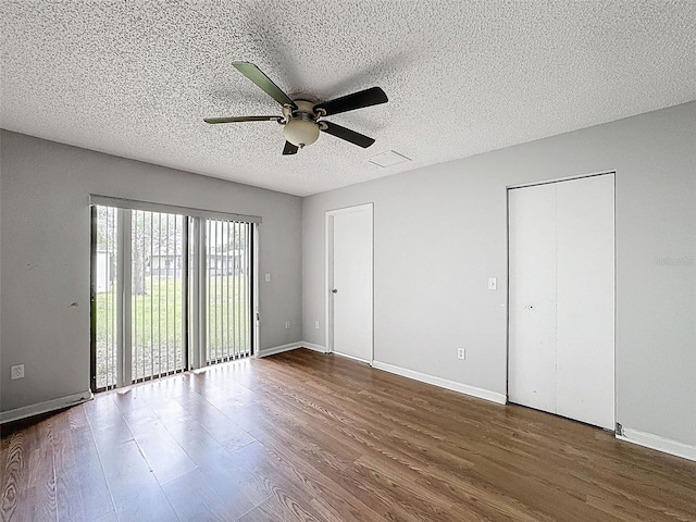 7337 Cone Shell Dr, Spring Hill, FL 34607 - unfurnished bedroom with dark wood-type flooring, baseboards, a textured ceiling, a ceiling fan, and multiple closets