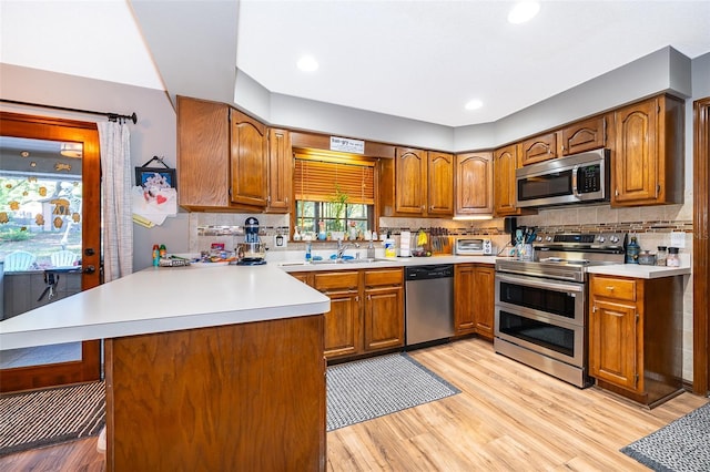 493 Princewood Dr, Deland, FL 32724 - kitchen featuring appliances with stainless steel finishes, brown cabinets, light wood finished floors, a peninsula, and recessed lighting