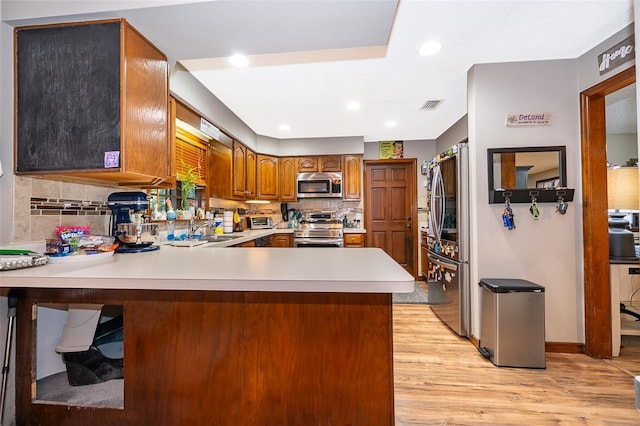 493 Princewood Dr, Deland, FL 32724 - kitchen with appliances with stainless steel finishes, a sink, a peninsula, light wood-style floors, and tasteful backsplash