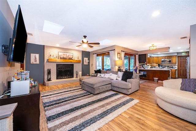 493 Princewood Dr, Deland, FL 32724 - living room with a skylight, a ceiling fan, light wood-style flooring, a fireplace, and recessed lighting